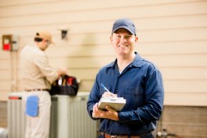 two technicians standing near outside unit of air conditioner with tools