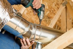 technicians hands drilling ductwork together